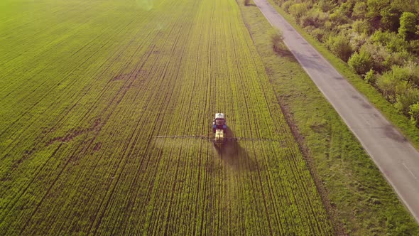 Aerial View of Farming Tractor Spraying on Field with Sprayer alt