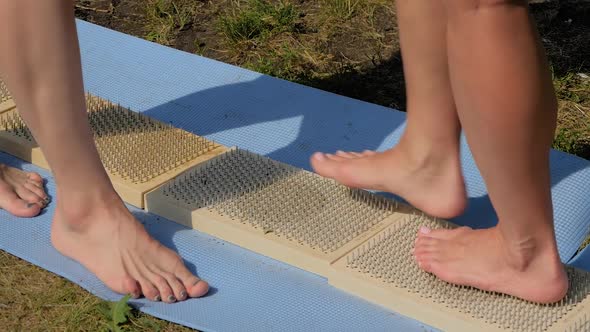 Woman Feet Walking Barefoot on Wooden Boards with Sharp Nails at Yoga Festival
