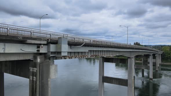 Bridge with birds flying and cars with dark clouds and dark blue water in Kitsap Bremerton