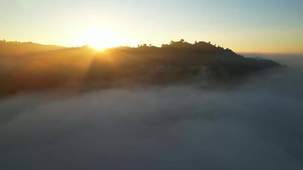 4K Aerial view flying in fog. the sun is hidden behind the clouds at sunset fog. alt