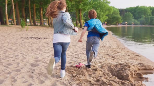 Two Kids Run Along Sandy Shore