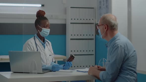 African American Woman Working As Doctor Holding Bottle of Pills alt