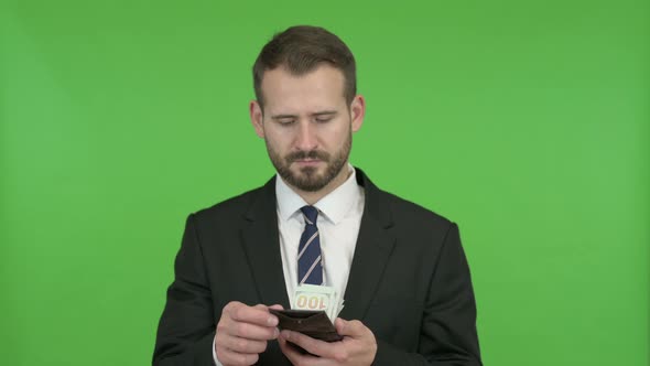 Young Businessman Showing Off Money From Wallet Against Chroma Key alt