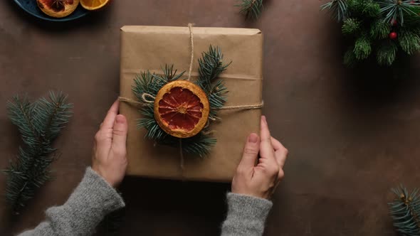 Woman Puts Christmas Present on Table alt