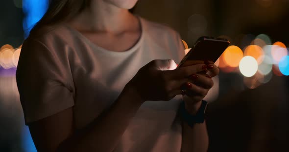 Close-up of a Mobile Phone in the Hands of a Girl in the City at Night alt