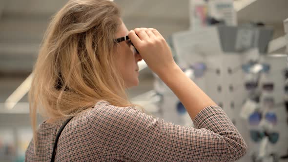 Woman Chooses Sunglasses In Store.Customer Shopaholic Girl Baying Fashion Eyewear On Retail Store. alt