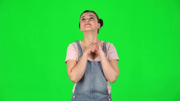 Lovely Girl Daydreaming and Smiling Looking Up Against Green Screen alt