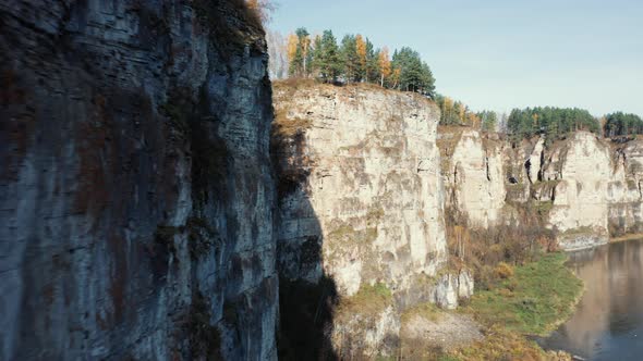 Aerial view; camera moving along rocky cliff of river