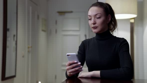 Doubting Woman is Sitting at Home with Mobile Phone Deciding Calling or Not Waiting Call alt