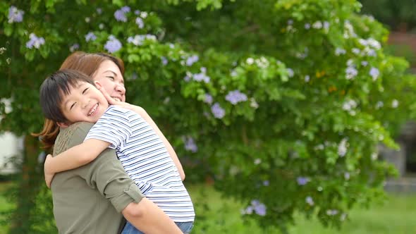 Happy Asian Mother Playing With Her Son In The Park alt