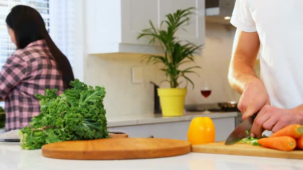 Man cutting vegetables and pregnant woman washing leafy vegetable in sink 4k alt