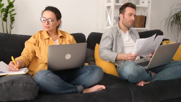 Couple Using Laptops for Remote Work on the Sofa at Home Focused Spouses Working on the Distance