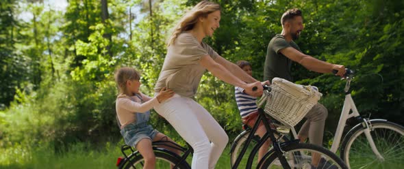 Video of playful family having fun on a bicycles in the woods. Shot with RED helium camera in 8K. alt