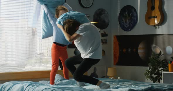 Boy and Girl Playing Pillow Fight on Bed alt