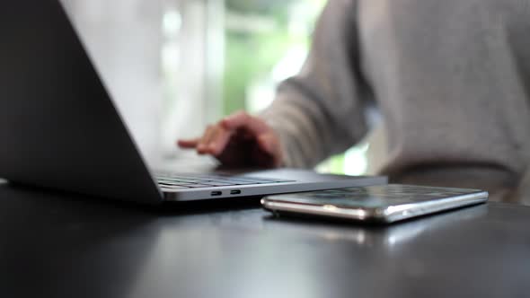 Closeup a woman working and touching on laptop computer touchpad and mobile phone on the table