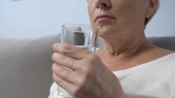 Aged Woman Taking Pill With Glass of Water, Vitamins and Supplements for Health