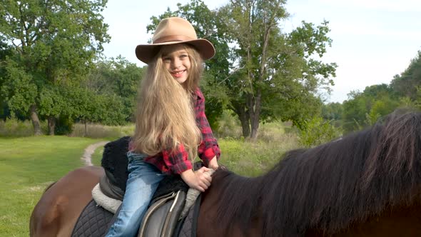 Young Cowgirl in Hat Riding Her Horse alt