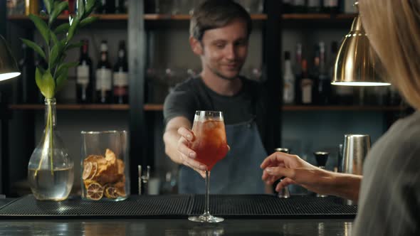 Woman Hands Toasting with Aperol Spritz Cocktails Woman in Bar Take Alcohol From Bartender alt