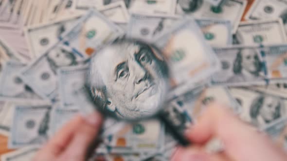 One Hundred Dollars Inspecting Under Magnifying Glass on Money Background alt