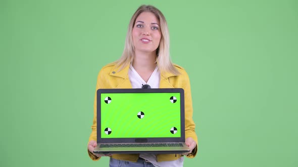 Happy Young Rebellious Blonde Woman Talking While Showing Laptop alt