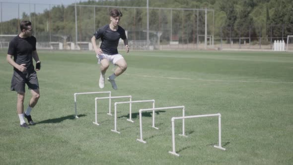 Personal trainer giving motivation to football player. training for jumping alt