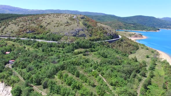 Aerial view of empty paved road passing artificial lake of Peruca, Croatia alt