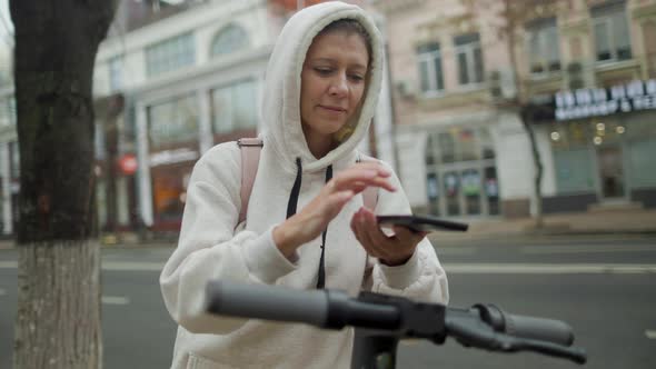 Woman Take Electric Kick Scooter Or Bike Bicycle In Sharing Parking Lot alt