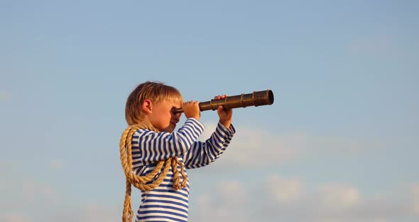 Kid with spyglass having fun outdoor against blue summer sky