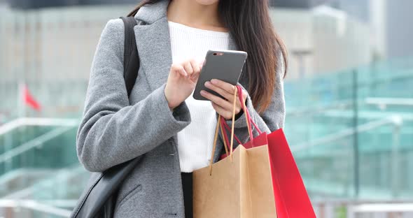 Woman use of mobile phone and holding shopping bag alt