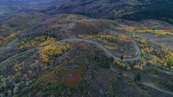 Aerial view of road winding through mountain landscape at sunset alt