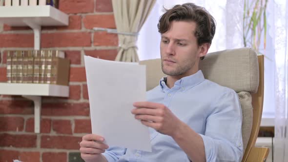 Disappointed Young Man Reading Documents alt