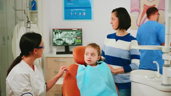 Doctor Showing to Child the Correct Dental Hygiene Using Mockup of Teeth Skeleton alt