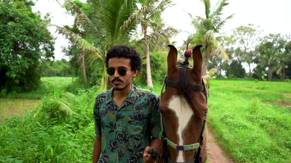Young handsome man with brown horse. alt