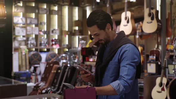 A Middle Eastern Man Using Mobile Phone To Purchase Product  alt