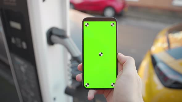 Slow motion green screen smart phone with electric car charging on street