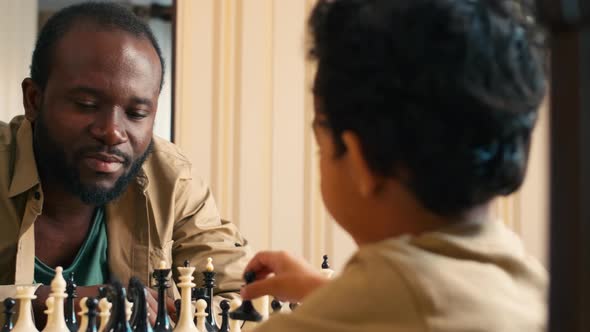 African American father playing checkmate with his son