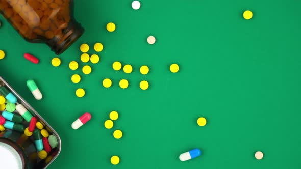 Medicines spilling out on green paper background top view