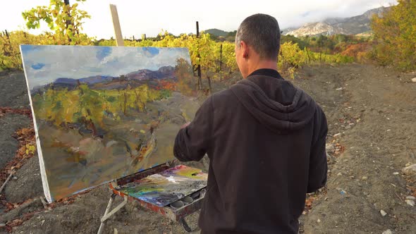 Man Artist in Front of Easel Outdoors Painting with Brushes Using Oil or Acrylic alt