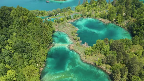 Top view of the Plitvice Lakes National Park with many green plants, beautiful lakes and a boat sail alt