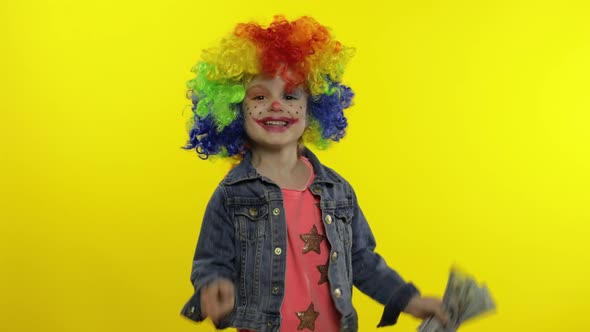 Child Girl Clown in Colorful Wig Dancing with Money Dollar Cash Banknotes. Fool Around, Smiling alt