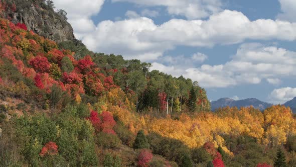 Clouds moving in time lapse over colorful fall mountainside alt