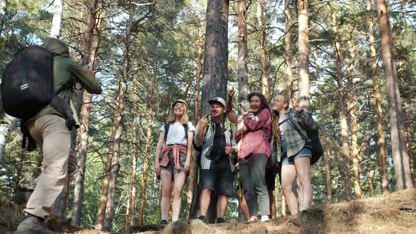 Slow Motion of Tourists Posing for Camera in Forest Having Fun While Man with Backpack Taking alt