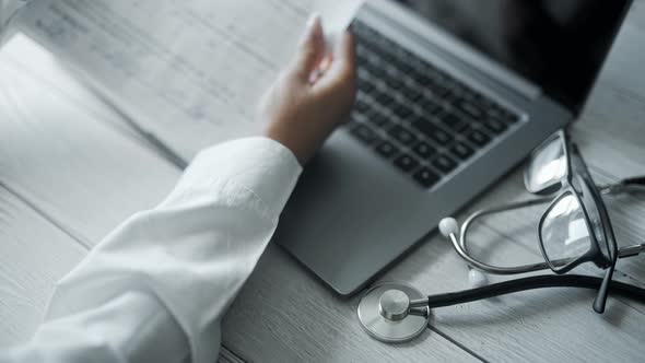 Close Up of a Doctor is Working and Typing on Laptop in a Clinic alt