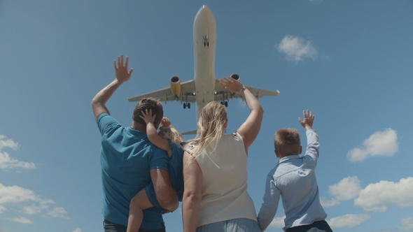 A young family greeting a plane, flying above