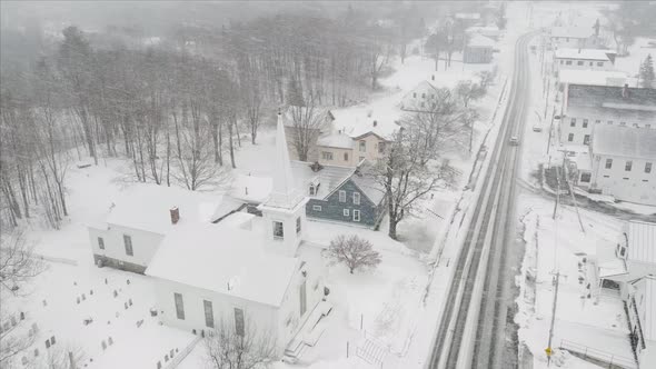 Blizzard snowfall over church small town aerial alt