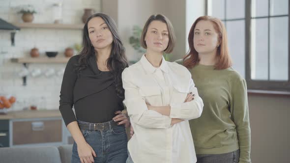Middle Shot of Three Confident Beautiful Caucasian Women Standing Indoors Looking at Camera alt
