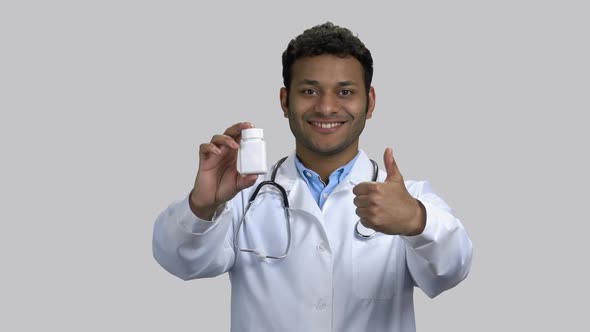 Portrait of Happy Darkskinnend Doctor with Medicine Bottle and Thumb Up alt