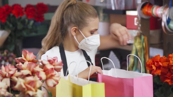 Female Florist Packs Boxes with Plants and Gifts in Colored Paper Bags Cheerful Woman Working in a alt