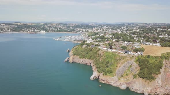 Flying over beautiful beach town in Torquay, England. Coastal town with harbour and Ferris Wheel in alt
