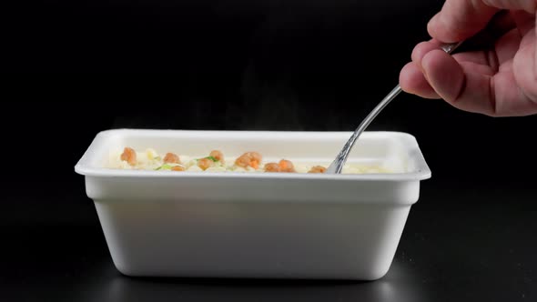Caucasian Hand with Fork Taking Cooked Instant Noodles From Styrofoam Container on Black Background